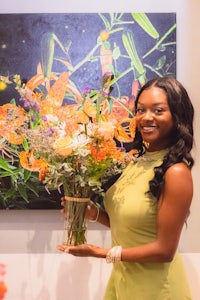 a woman holding a bouquet of flowers in front of a painting